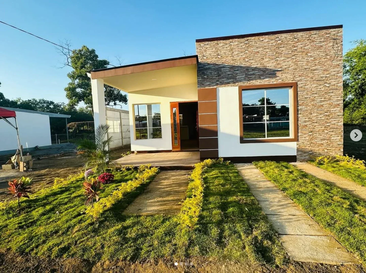 Casa con fachada de piedra laminada, marcos marrones y porche